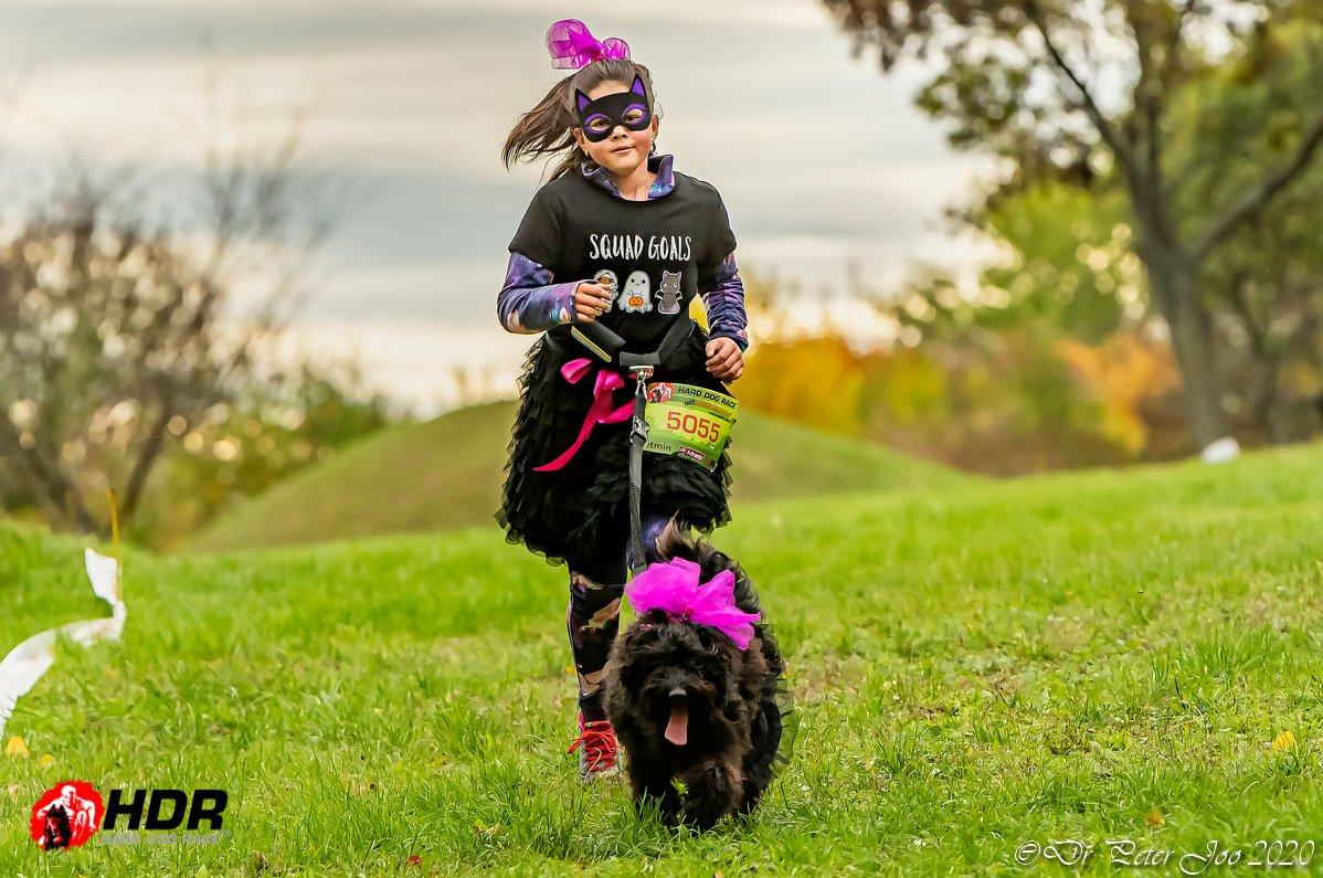 Kislány jelmezben kutyájával fut